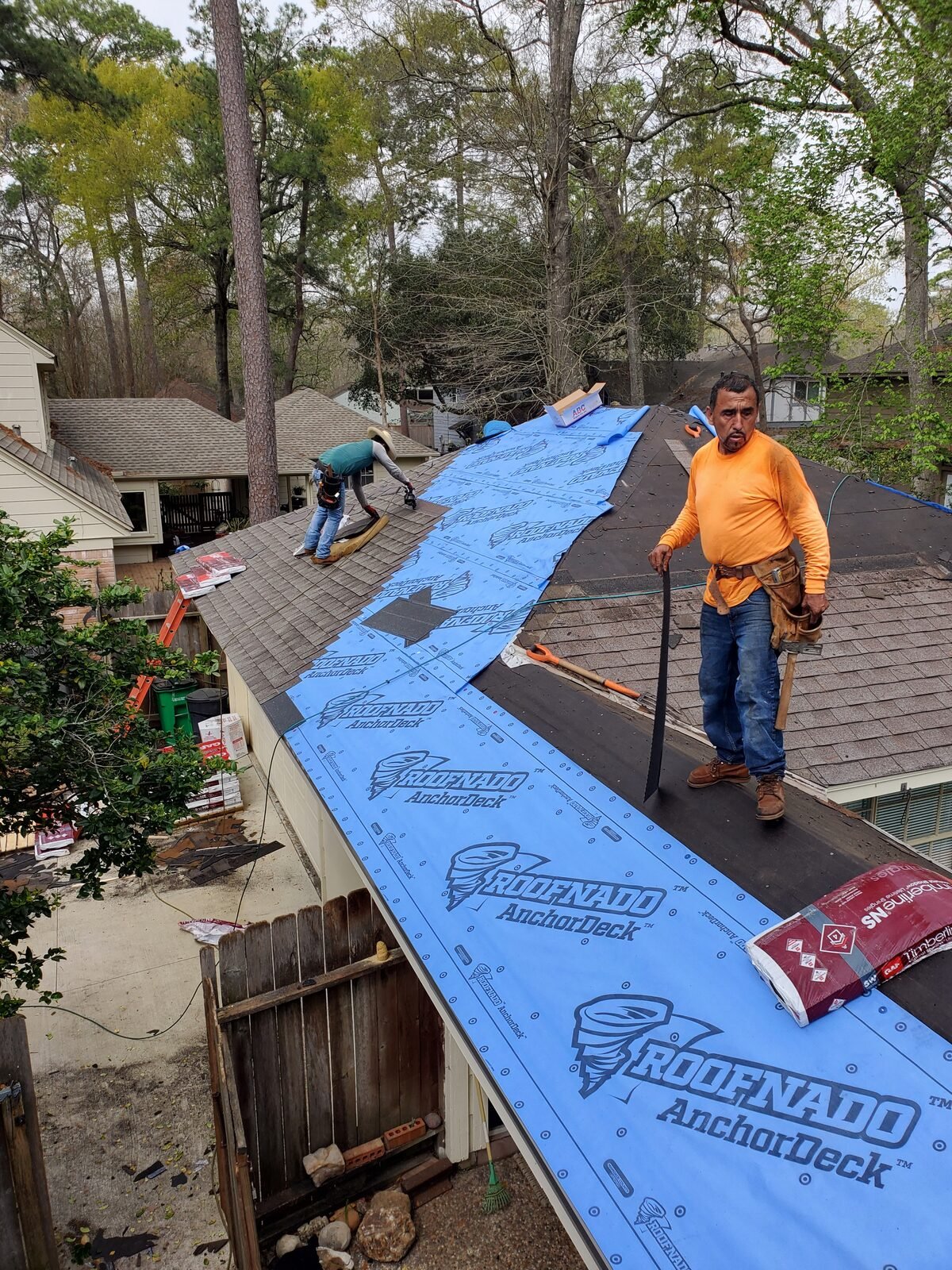 Roofer carrying shingles across a roof covered in new underlayment