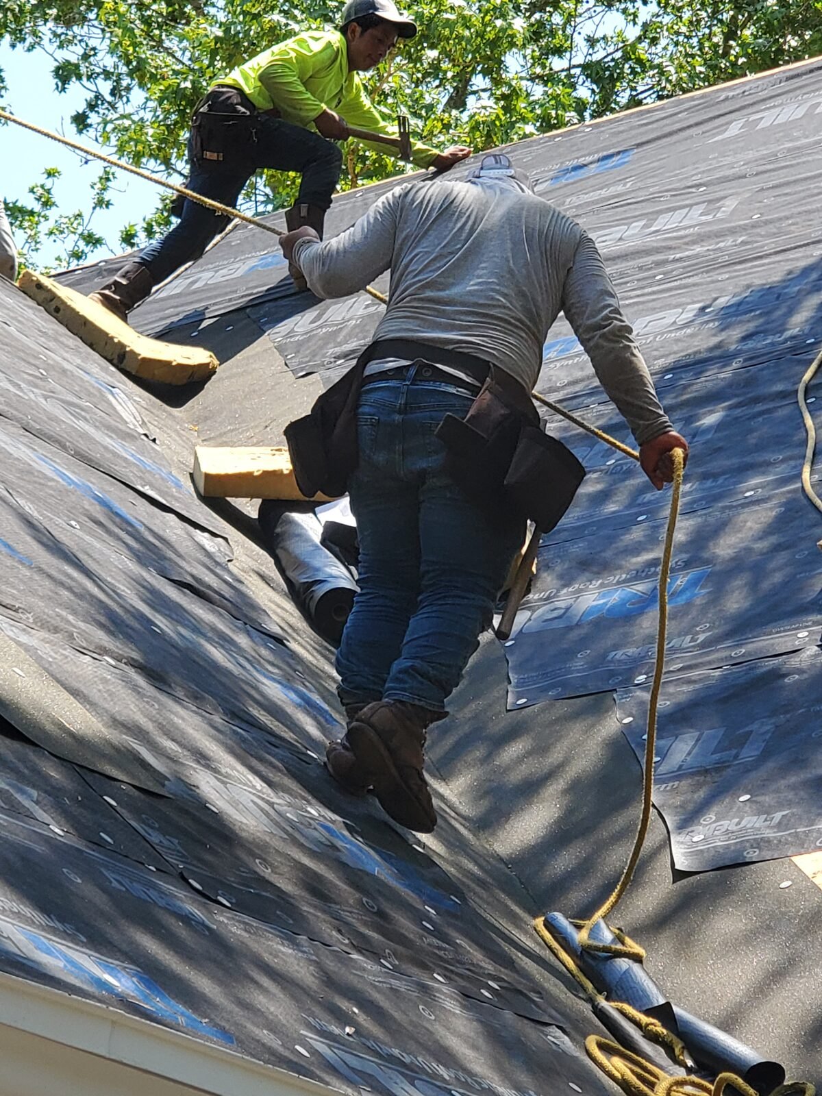 Triple G roofers installing synthetic underlayment on a steep roof