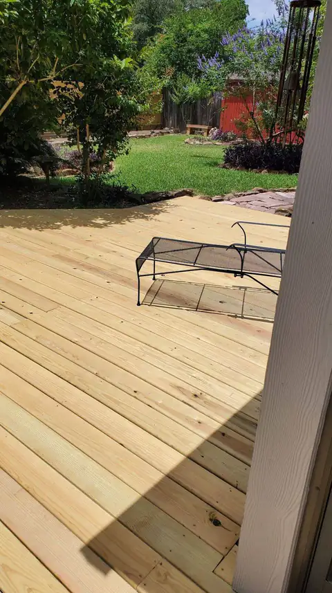 New pressure-treated wood deck wrapping a backyard