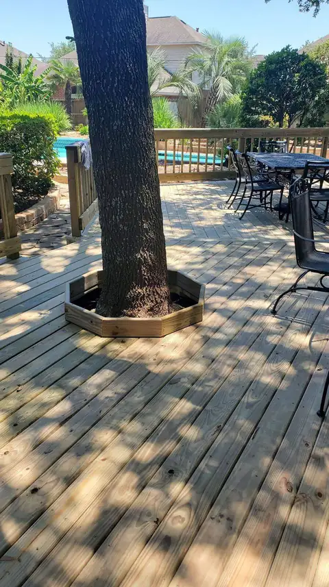 Wood deck built around a mature tree with custom railing