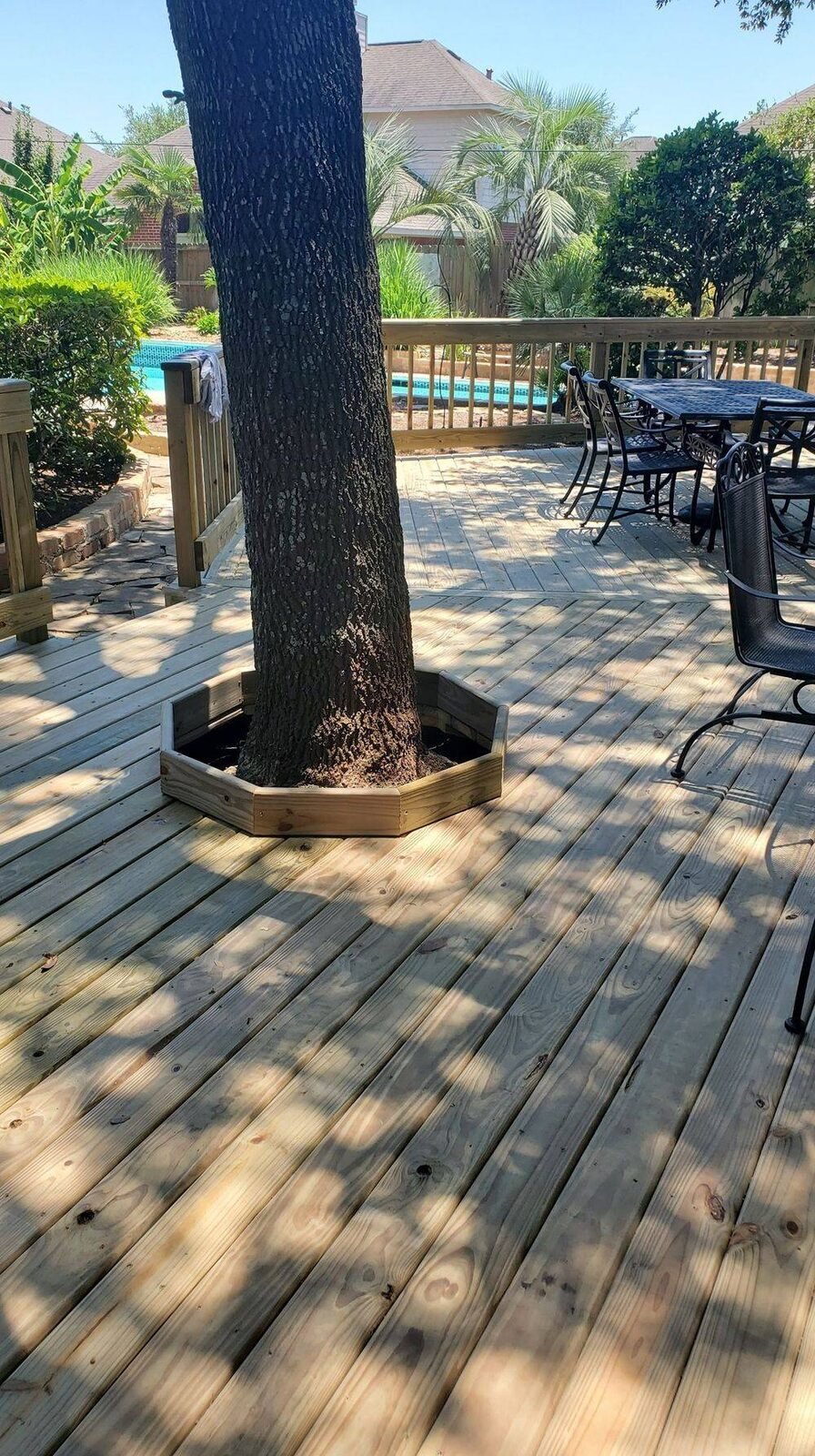 Wood deck built around a mature tree with custom railing