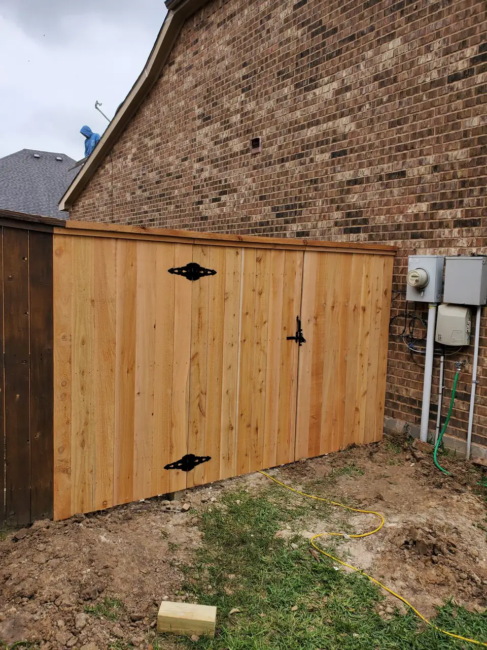 New cedar fence and double gate beside a brick home