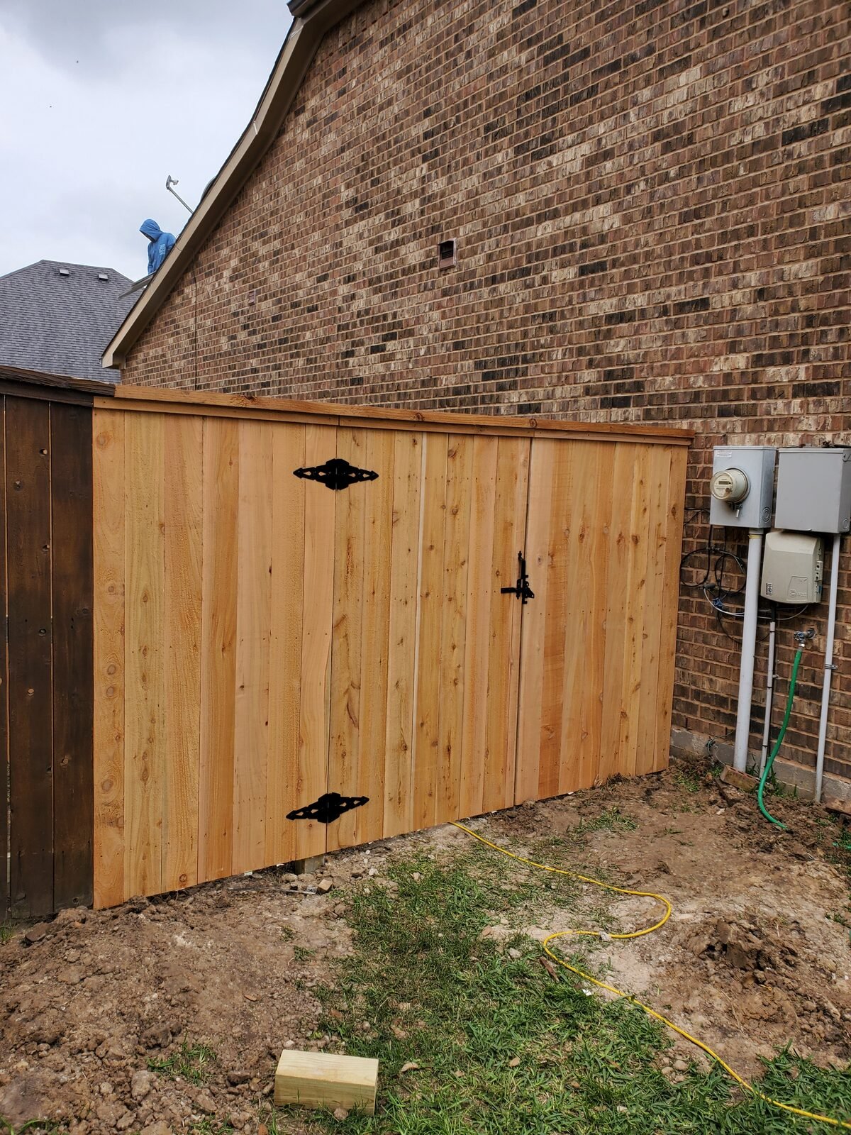 New cedar fence and double gate beside a brick home