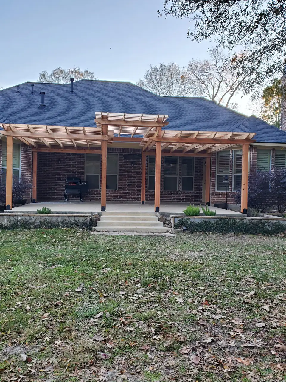Custom cedar pergola over a back patio on a brick home