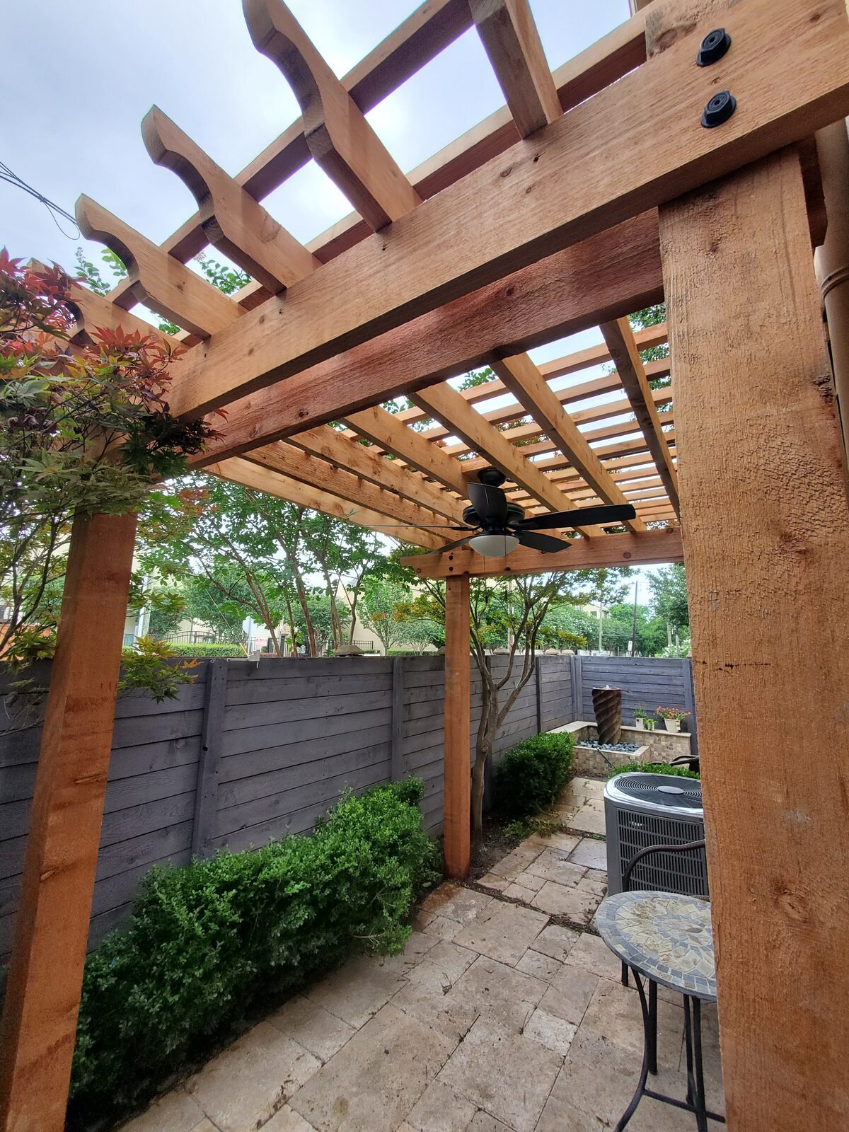 Cedar pergola with decorative rafter tails over a side patio