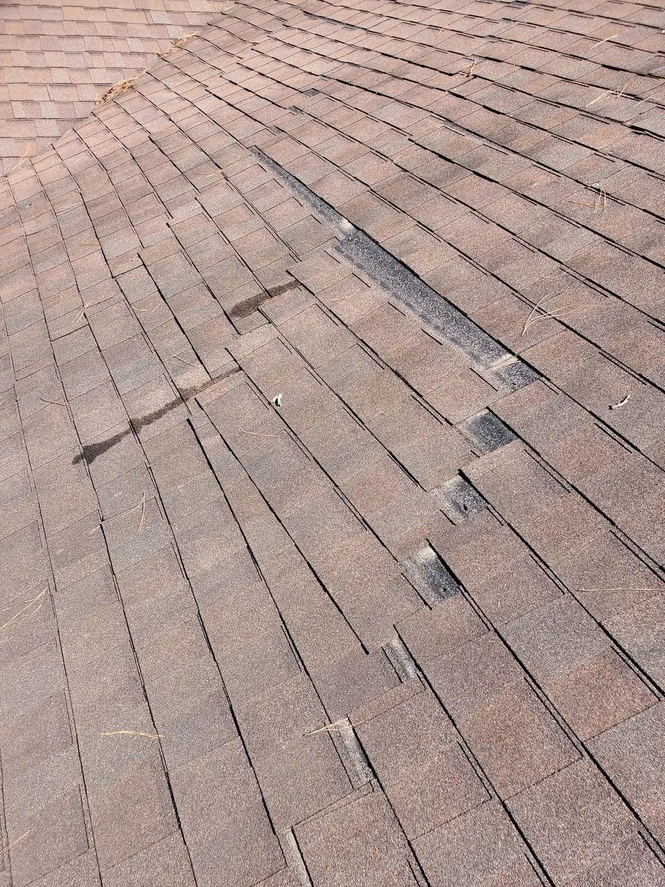 Close-up of cracked and lifted shingles found during a roof inspection