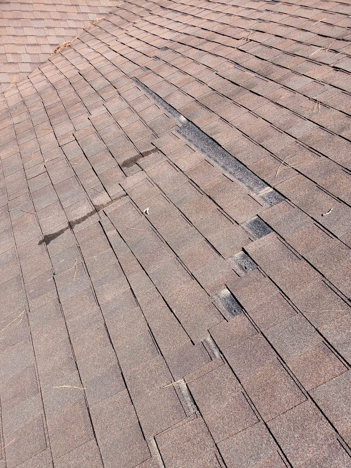 Close-up of cracked and lifted shingles found during a roof inspection