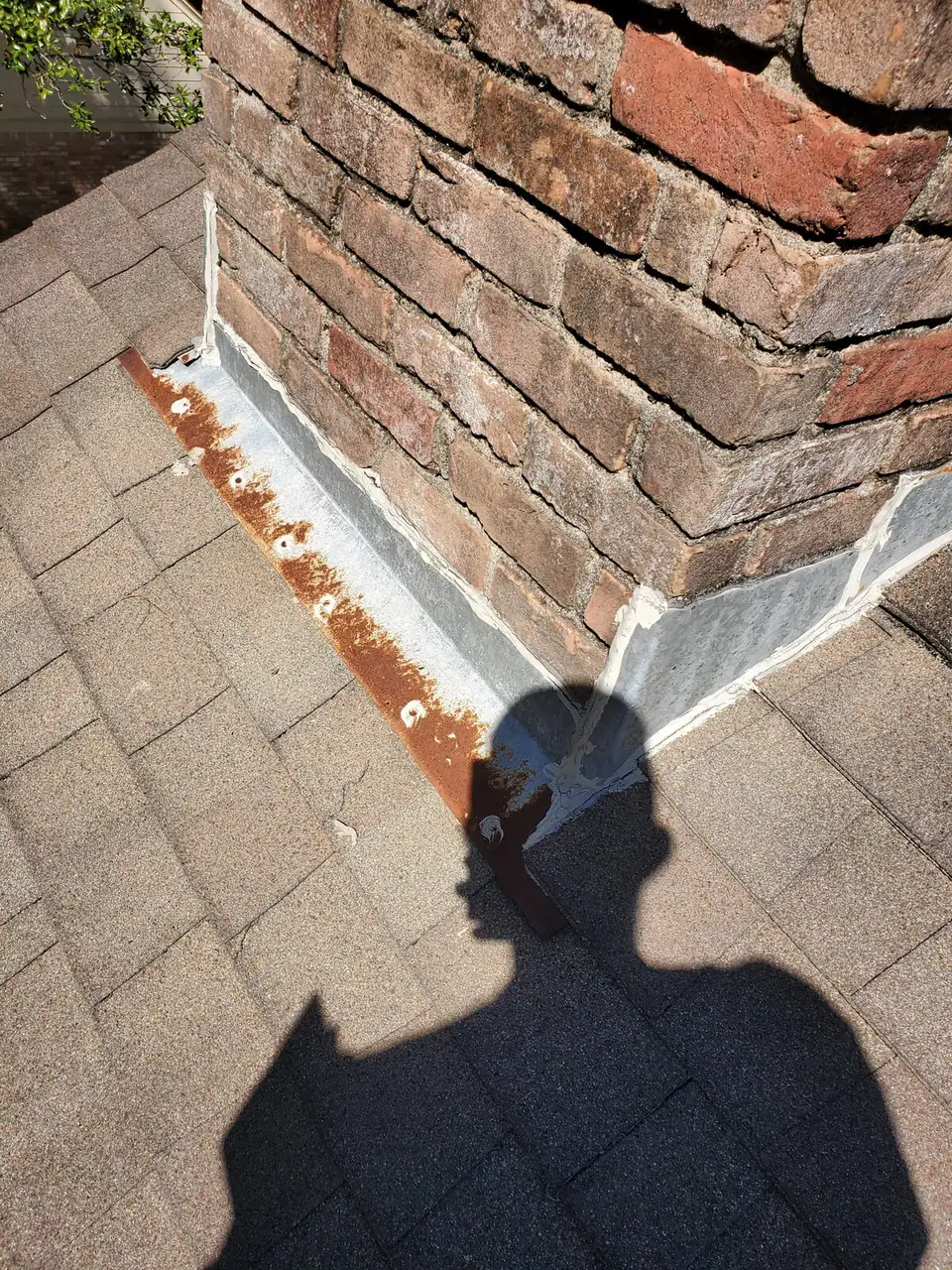 New step flashing sealed against a brick chimney during a roof repair