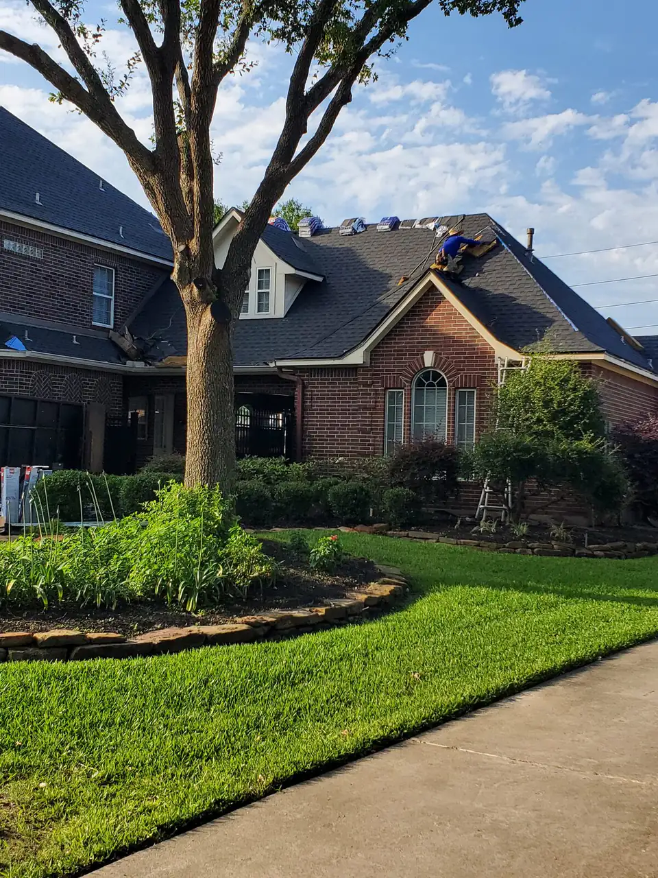 Two-story brick home during a roof replacement